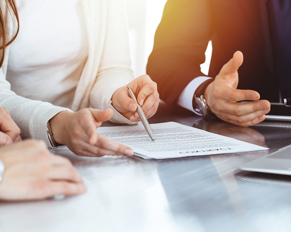 Signature de contrat : négociation et conseils juridiques Mains pointant un contrat lors d'une réunion d'affaires pour une signature ou une négociation juridique.
